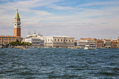 Buildings at waterfront against cloudy sky