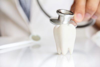 Midsection of doctor analyzing dentures with stethoscope on table