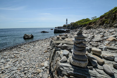 A small pebble tower built on the shore close to a lighthouse