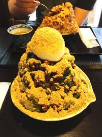 Close-up of hand holding ice cream served on table