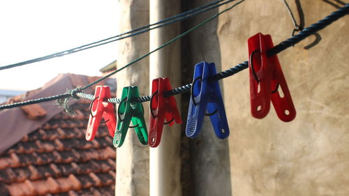 Low angle view of clothespins hanging on rope against wall