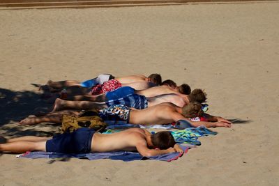High angle view of friends lying on sandy beach