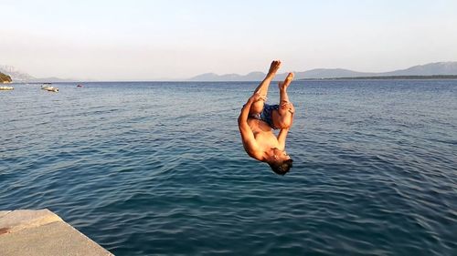 Upside down image of man surfing in sea against sky