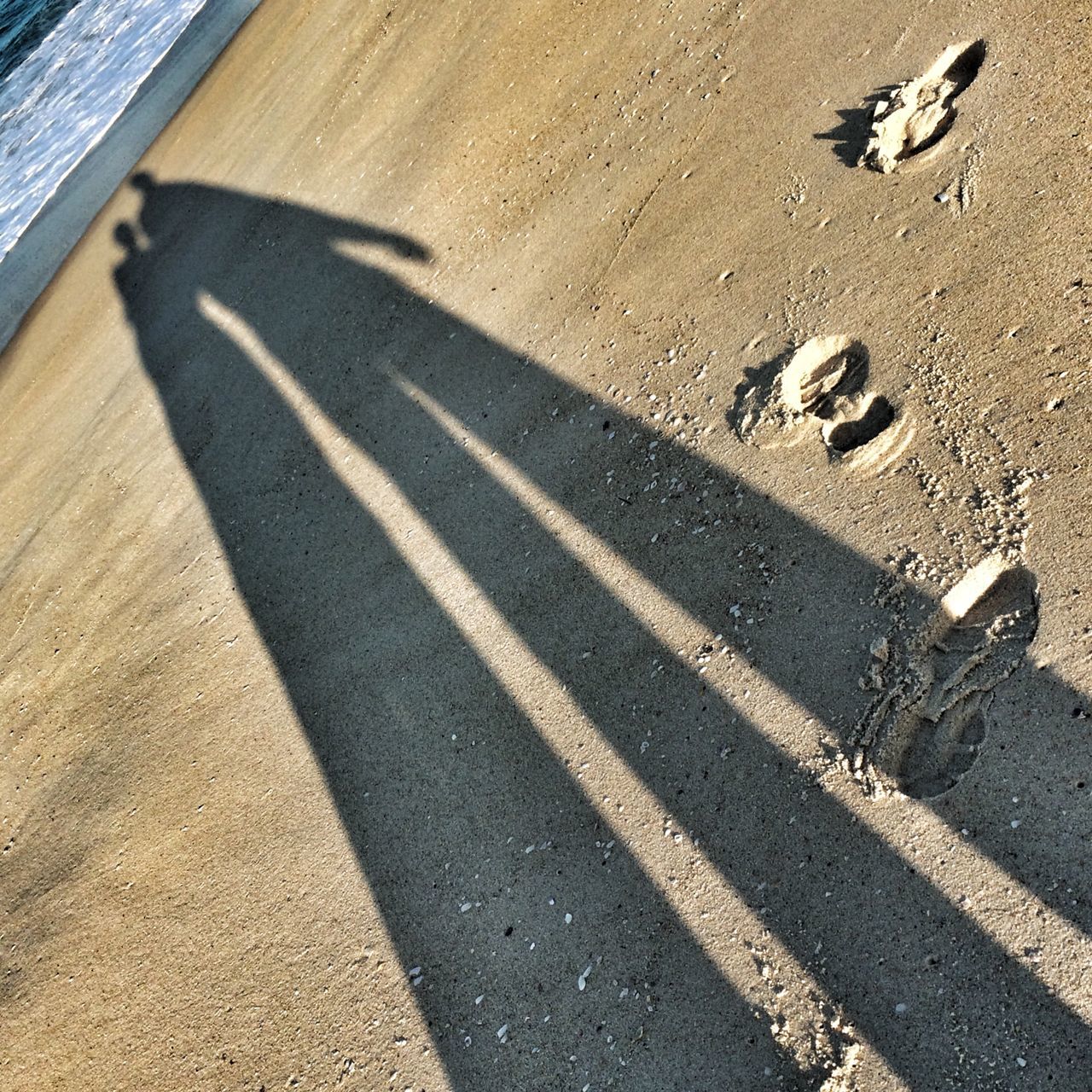 high angle view, street, shadow, road, road marking, sunlight, asphalt, transportation, day, outdoors, sand, no people, focus on shadow, ground, sidewalk, elevated view, sunny, communication, textured, guidance