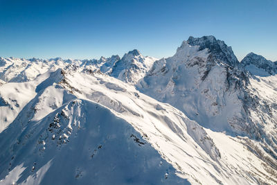 Snowy slope of dombay mountains under clear sky