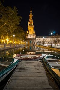 Boats moored on lake against illuminated plaza de espana at night