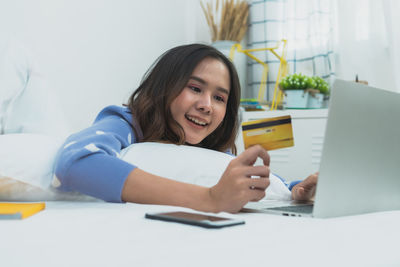 Portrait of young woman using phone while sitting on table