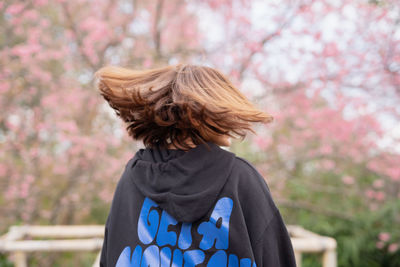 Rear view of woman shaking head in park