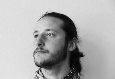 Portrait of young man looking away against wall