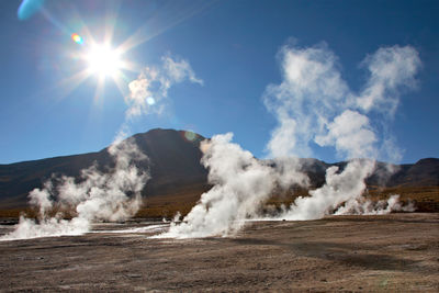 Smoke emitting from volcanic landscape against sky