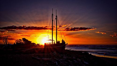 Silhouette boats moored on sea against orange sky