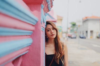 Portrait of young woman standing against building