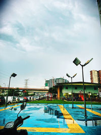 Street by swimming pool in city against sky