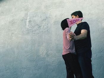 Couple kissing against wall