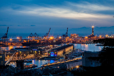 Illuminated cityscape by sea against sky at night