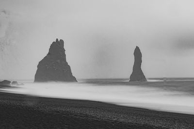 Rock formations on beach against sky