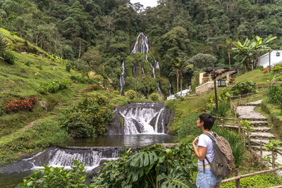 Rear view of woman standing against waterfall