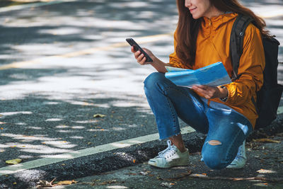Low section of woman using mobile phone