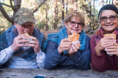 Portrait of senior women with friend having food at forest