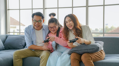 Full length of woman using mobile phone while sitting on sofa