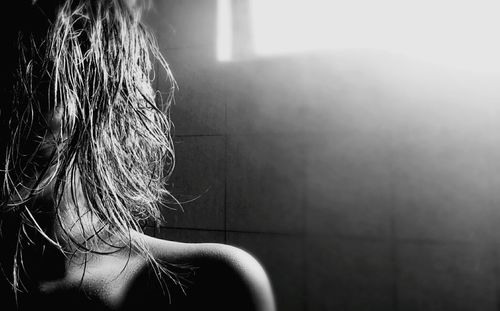 Close-up of woman standing against tiled wall