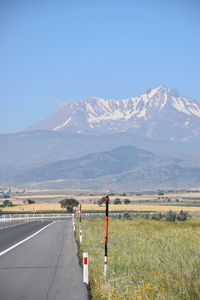 Road leading towards mountains against clear sky