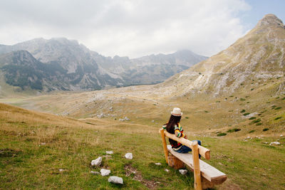 Man sitting on mountain against sky