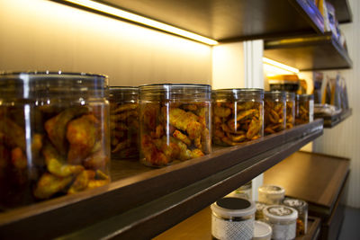 Spicy dry fruit cashew nuts packed in glass bottle arranged in racks in shop