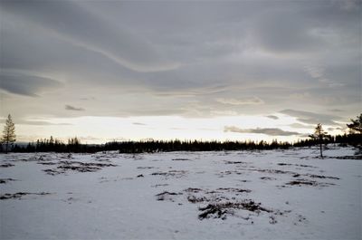 Scenic view of frozen landscape against sky during winter