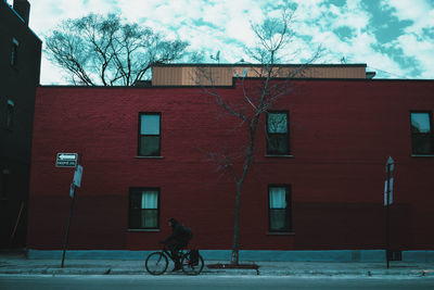 Man riding bicycle on street against building in city