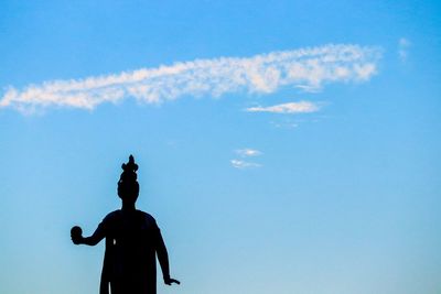 Low angle view of silhouette statue against blue sky