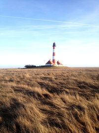 Lighthouse on field against sky