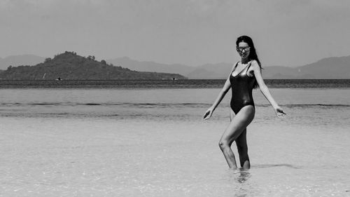 Full length portrait of young woman standing against sky