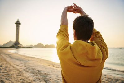 Rear view of women standing at beach during sunset