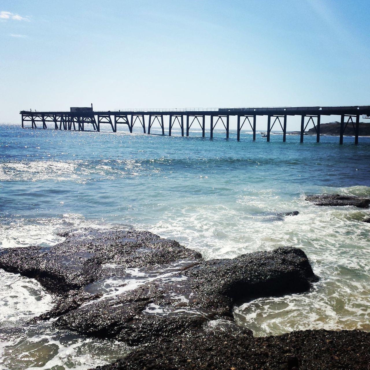 water, sea, beach, wave, shore, pier, horizon over water, surf, scenics, nature, beauty in nature, sky, tranquility, tranquil scene, clear sky, idyllic, sand, motion, sunlight, outdoors