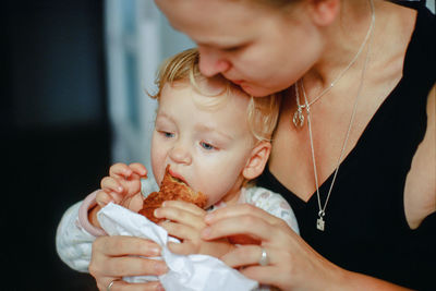 Close-up of cute baby girl eating food by mother at home