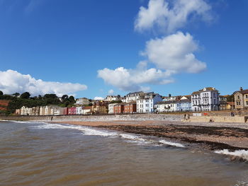 Buildings by sea against blue sky