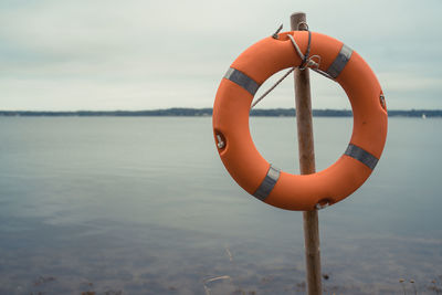 Life belt hanging on pole against lake