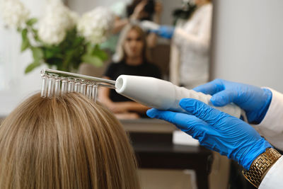 Doctor examines head skin of a young girl with special dermatology equipment system, hair loss and