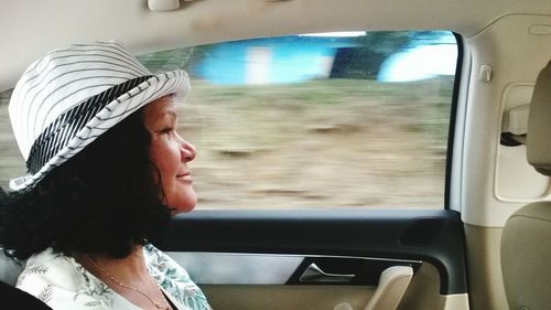 Side view of smiling mature woman sitting in car