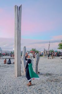 People at beach against sky during sunset