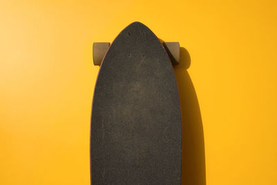 Close-up of skateboard on yellow against orange background