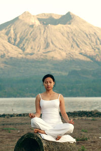 Woman doing yoga against mountains