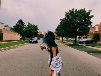 Full length of woman with umbrella on street in city against sky