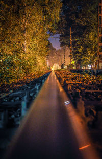 Road amidst trees against sky at night