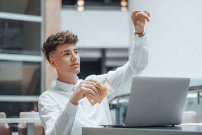 Side view of young businesswoman using laptop while sitting in office