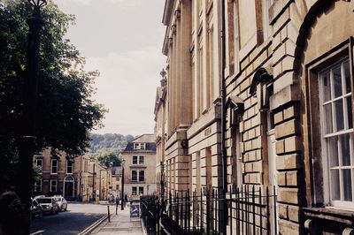 Street by buildings in city against sky