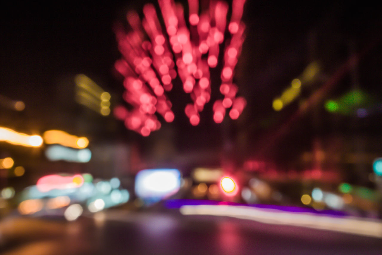 DEFOCUSED IMAGE OF ILLUMINATED CITY AGAINST SKY