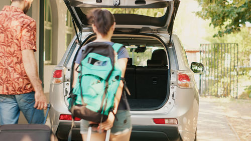 Rear view of woman standing in car