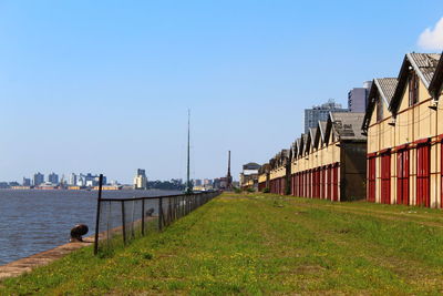 Buildings by sea against clear blue sky